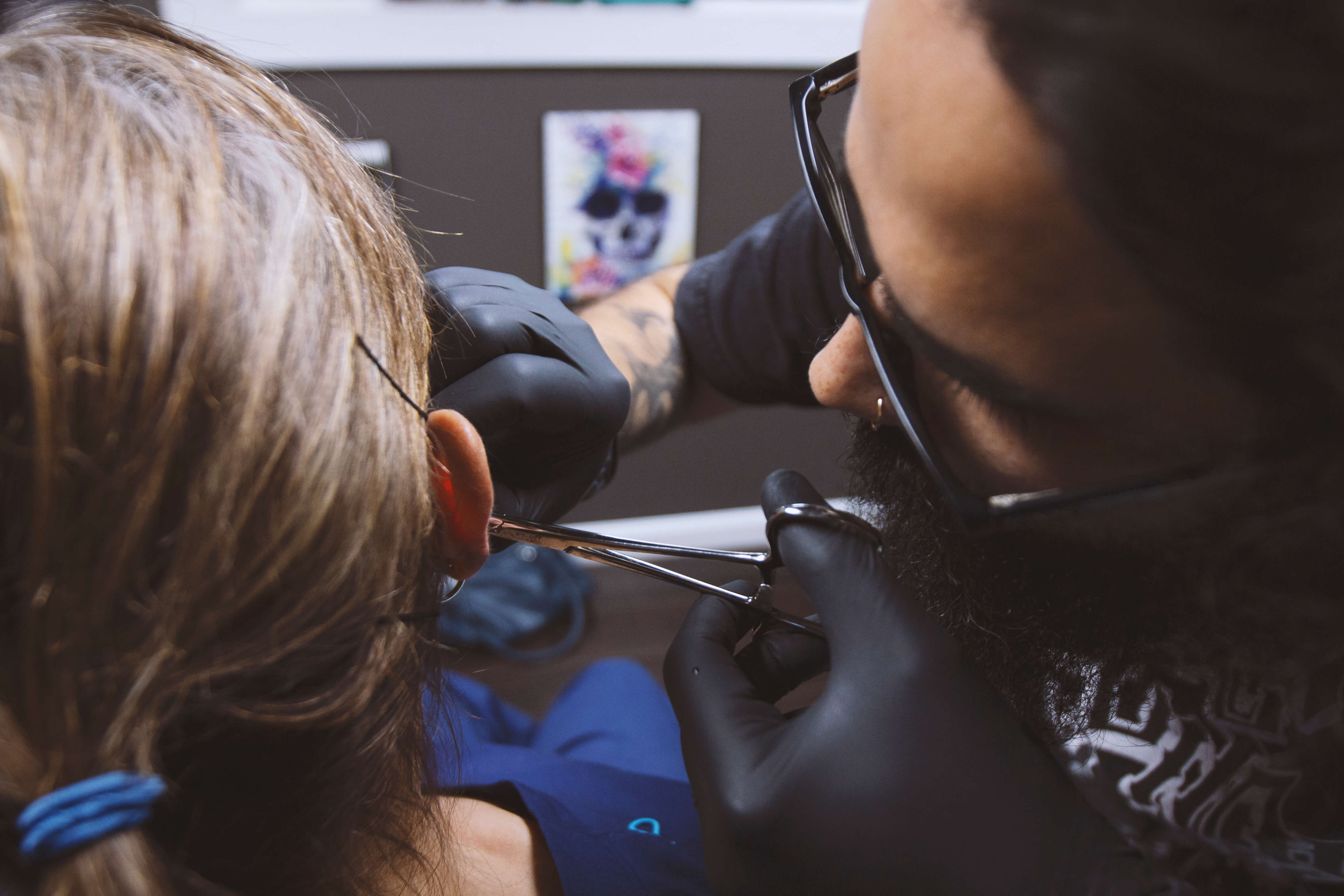 Ear piercing procedure by tattooed artist.